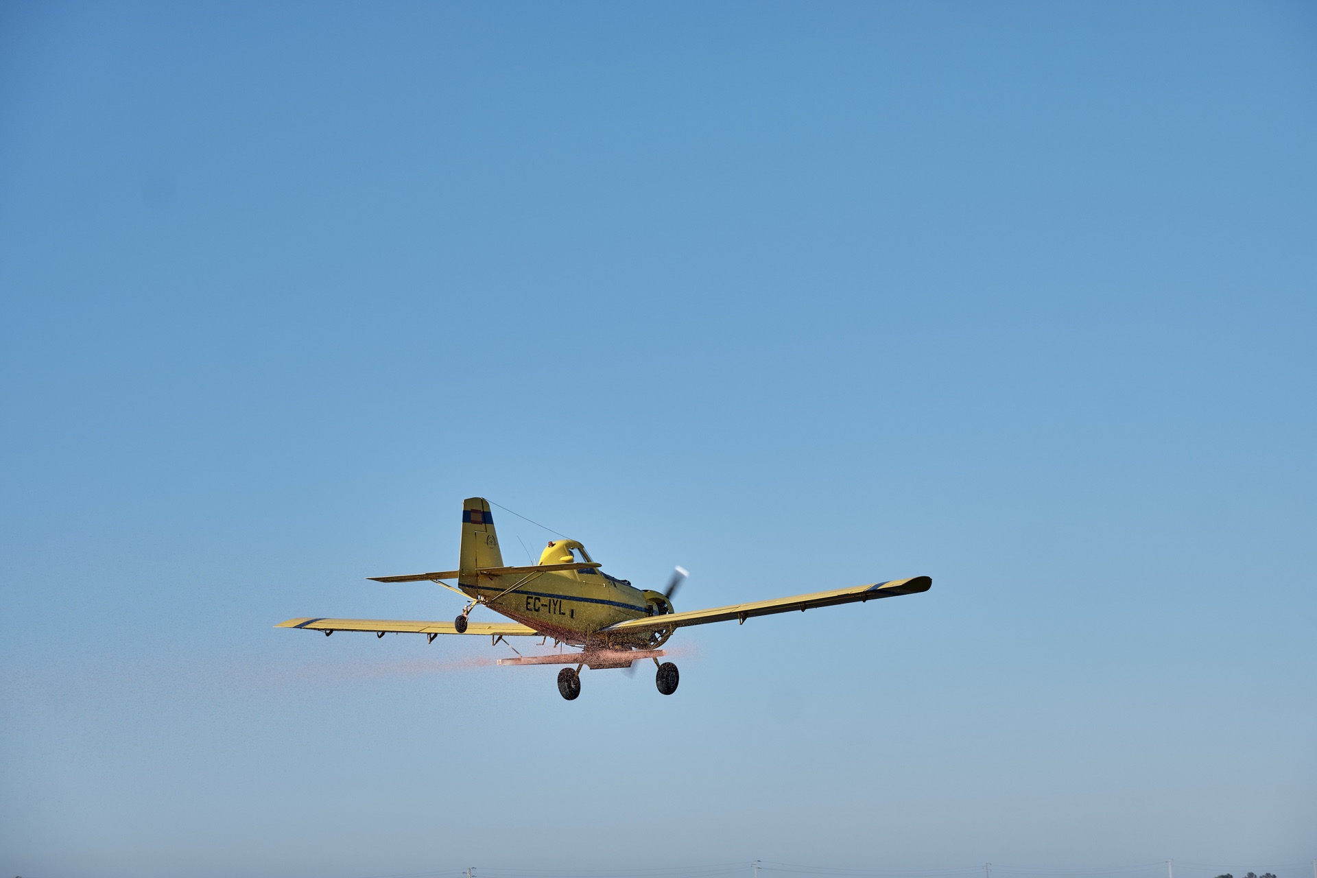 Gult enmotorigt propellerflygplan mot en klarblå himmel