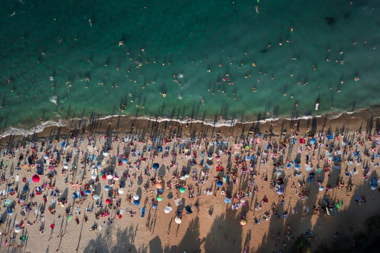 Välbesökt badstrand en sommardag sedd rakt uppifrån